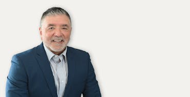 Ben Porras smiling and wearing a blue sports coat over button up shirt