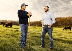 Austin Mooneyham and farmer standing in cattle field at golden hour