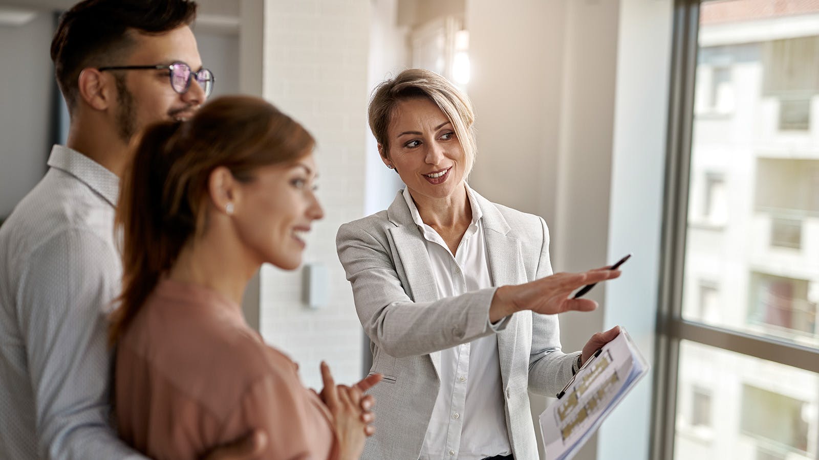 Smiling female real estate agent talking with a couple interested in buying a new home