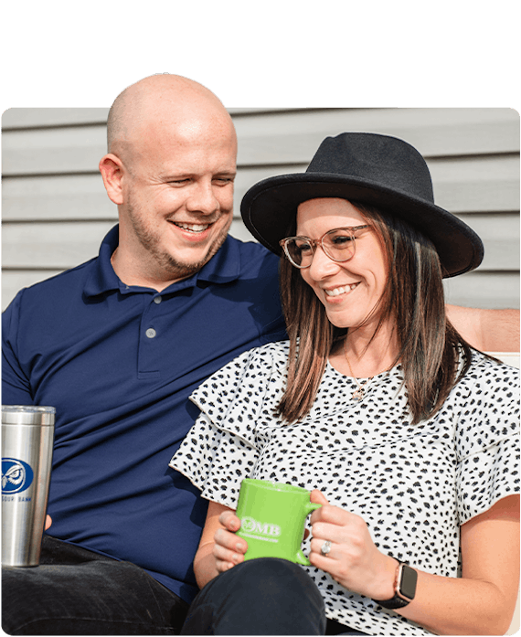 A young couple is sitting on their porch drinking coffee from OMB mugs and enjoying each others company