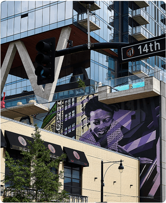 Downtown Kansas City with the 14th st street sign and a building covered in windows and purple colored mural in the background
