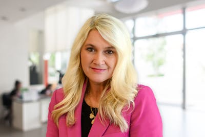 Michelle Sullivan wearing a pink blazer over a black top with office in the background