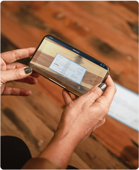 A woman is scanning a check for mobile check deposit in the OMB mobile banking app