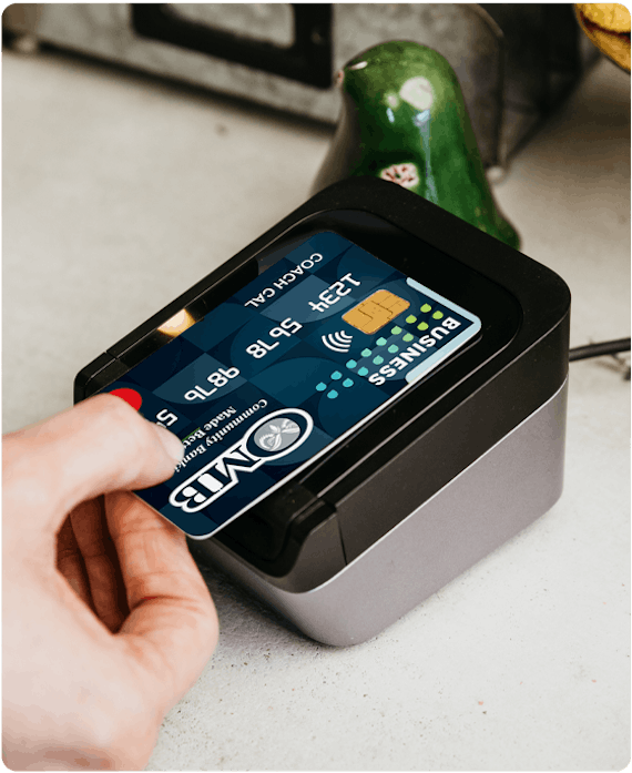 a close up of a person using the tap to pay feature with an OMB Bank business debit card