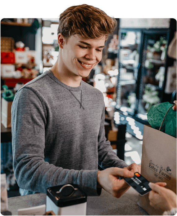 a teen boy using his Greenlight debit card to purchase an item