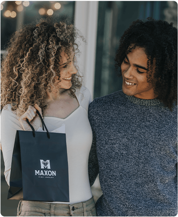 a multiracial couple walking out of jewelry store holding a black shopping bag