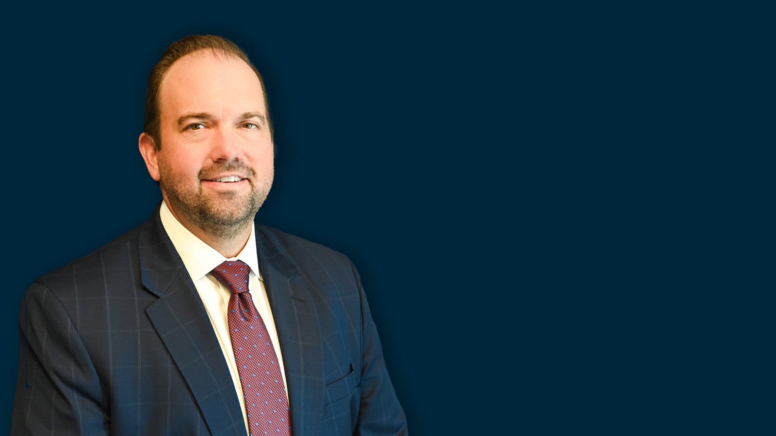 Trevor Crist wearing a navy sports coat and maroon tie