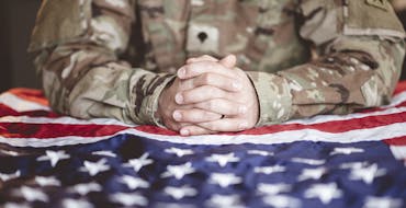 Solider with hands clasped on an American flag