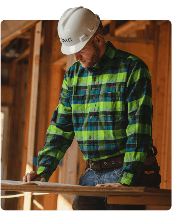 Construction worker in teal and lime plaid shirt and OMB hard hat in work zone
